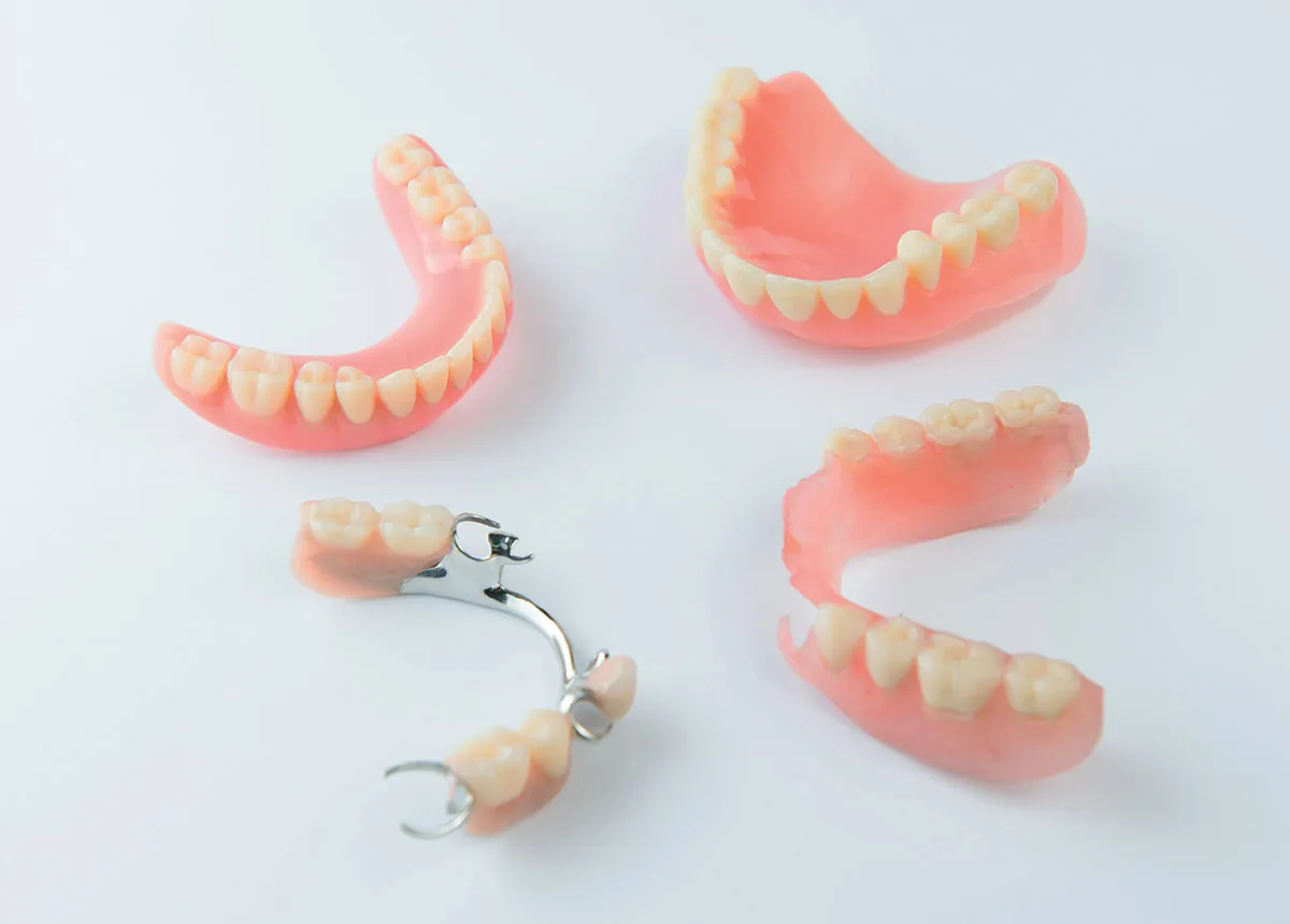 Two removable dentures: a partial denture with metal clasps and a complete denture with a pink gum-coloured base